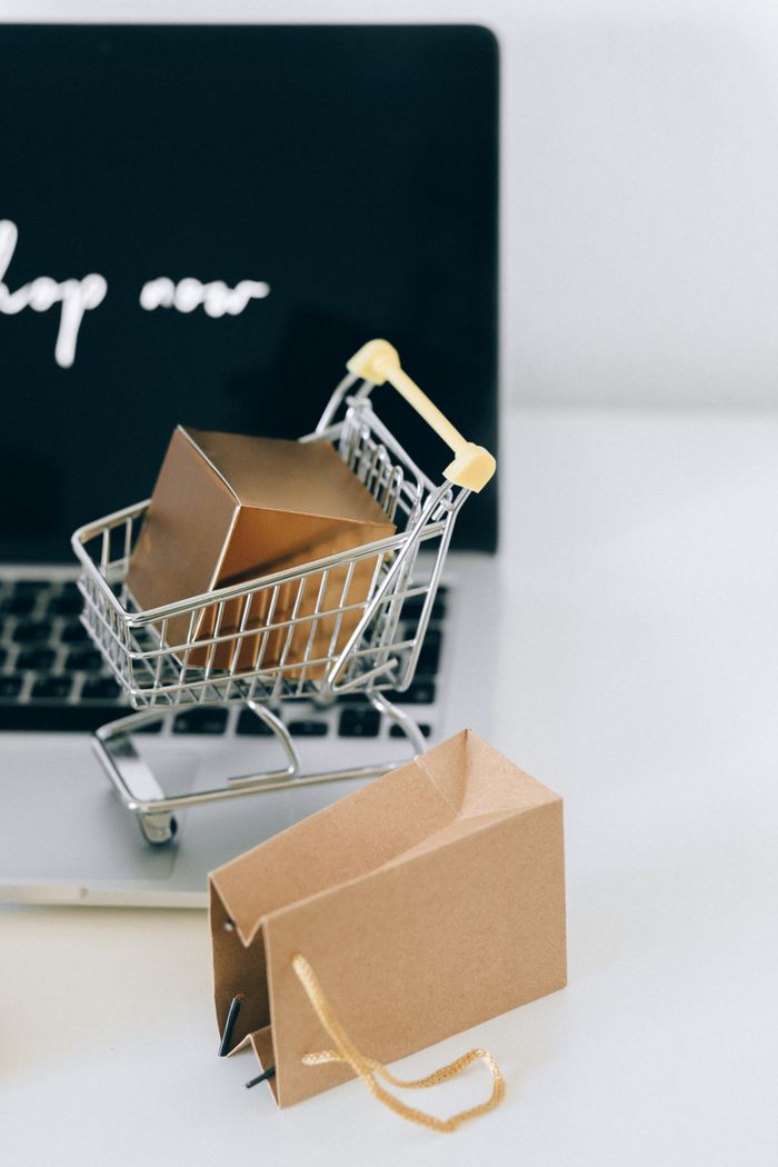 who-we-are A miniature shopping cart with a parcel on a laptop symbolizes online shopping and e-commerce.